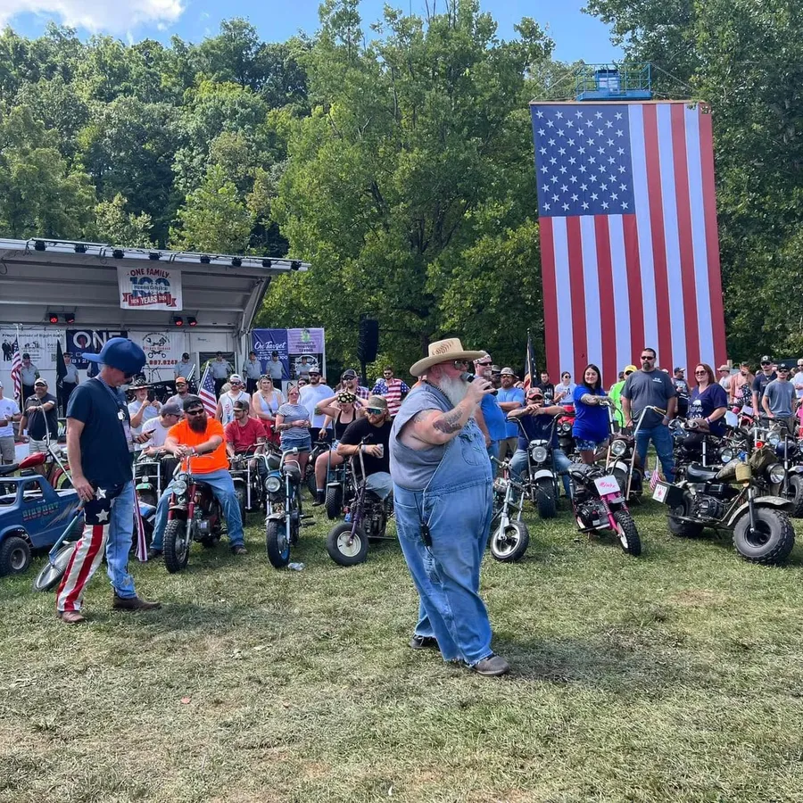Biggin Noble addressing the crowd with mini rigs and the American flag behind him