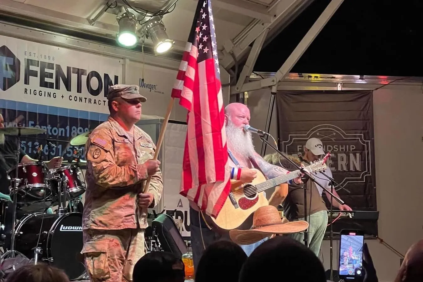 A color guard carries the flag onstage as a band performs