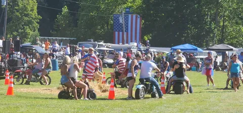 A lineup of custom mini bikes in front of the giant American flag before the parade