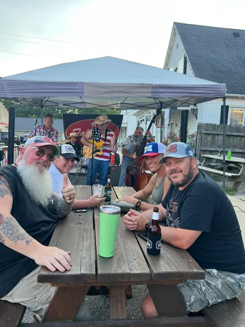 A band playing at Friendship Tavern's street party under a tent, with festival-goers seated at picnic tables